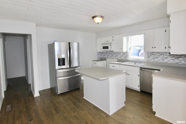 kitchen with stainless steel appliances, a center island, sink, backsplash, and white cabinets