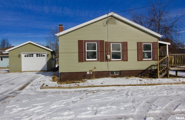 snow covered property featuring a garage and an outbuilding