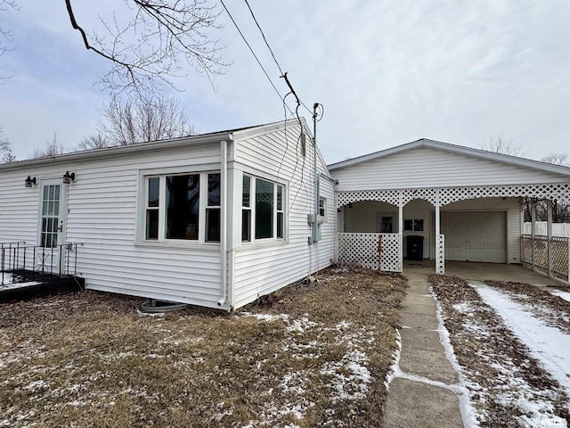 view of snow covered exterior with a garage and a carport