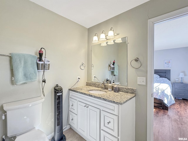 ensuite bathroom with ensuite bathroom, toilet, wood finished floors, and vanity