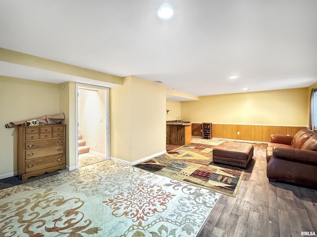 living room with wooden walls, a wainscoted wall, recessed lighting, wood finished floors, and stairs