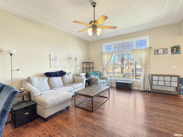 living area featuring a ceiling fan, dark wood finished floors, a textured ceiling, and baseboards