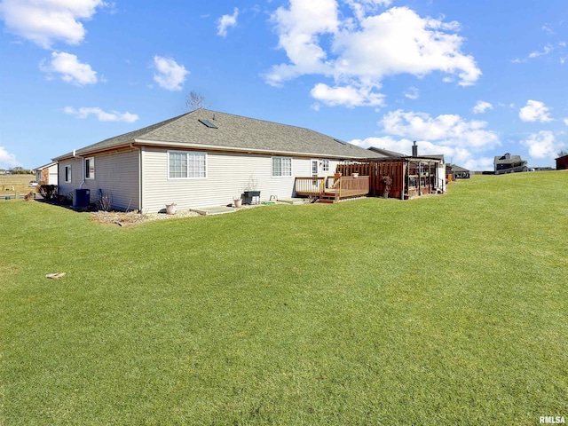 rear view of house with a wooden deck, roof with shingles, cooling unit, and a yard