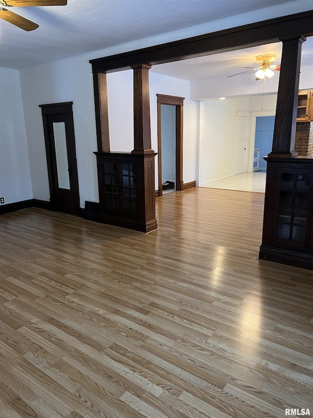 unfurnished living room featuring decorative columns, ceiling fan, and light hardwood / wood-style flooring