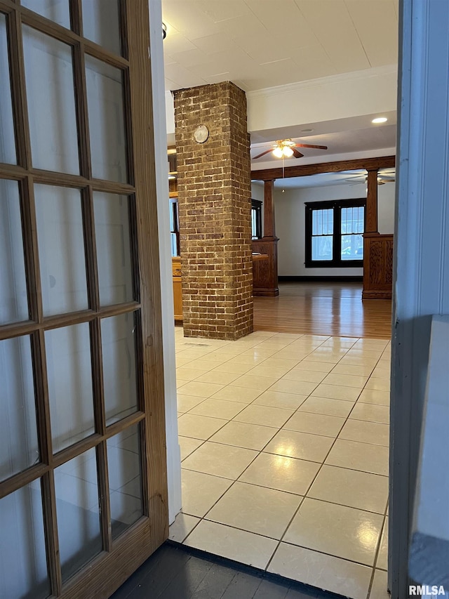 hall featuring brick wall, ornate columns, and tile patterned floors