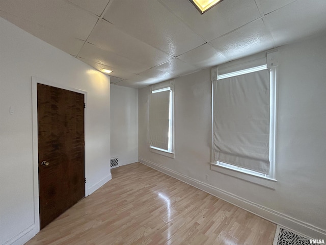 unfurnished room featuring light wood-type flooring and a paneled ceiling