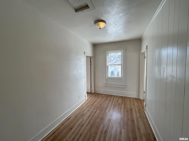 spare room featuring light hardwood / wood-style flooring and a textured ceiling