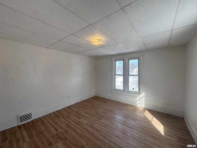 empty room featuring wood-type flooring and a paneled ceiling