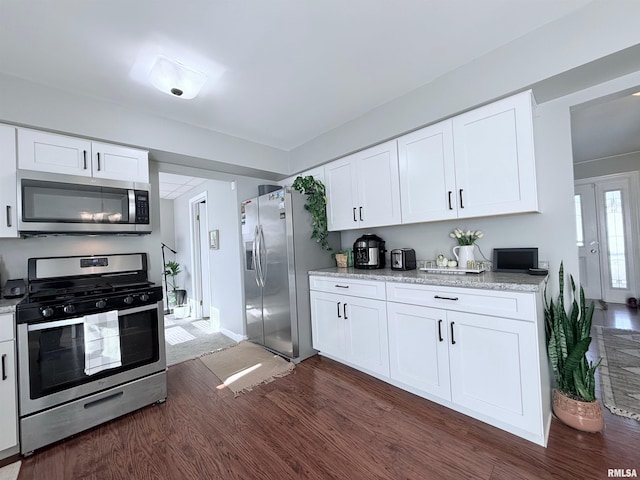 kitchen featuring white cabinetry, stainless steel appliances, light stone counters, and dark hardwood / wood-style floors