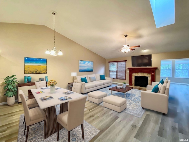 dining room featuring ceiling fan with notable chandelier, hardwood / wood-style flooring, a fireplace, and lofted ceiling