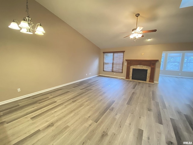 unfurnished living room featuring a fireplace, ceiling fan with notable chandelier, high vaulted ceiling, and light hardwood / wood-style flooring