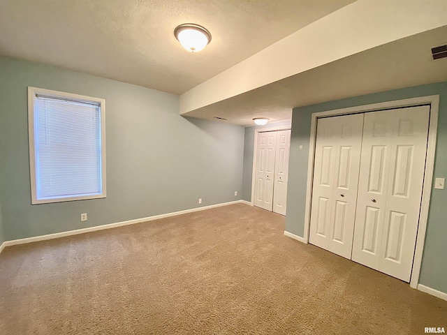 unfurnished bedroom with carpet, multiple closets, and a textured ceiling