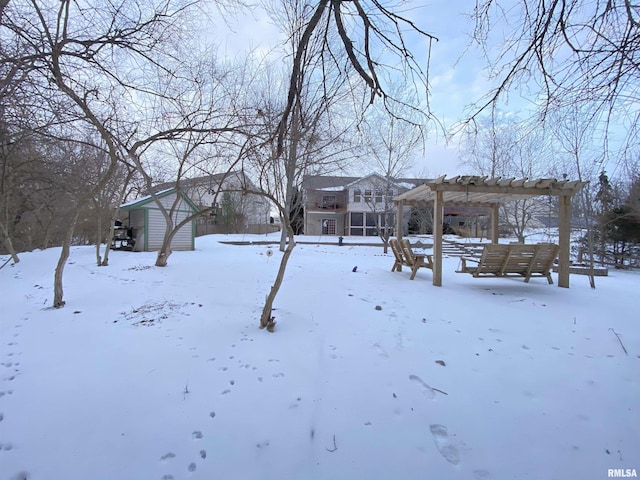 yard layered in snow with a pergola and a storage shed