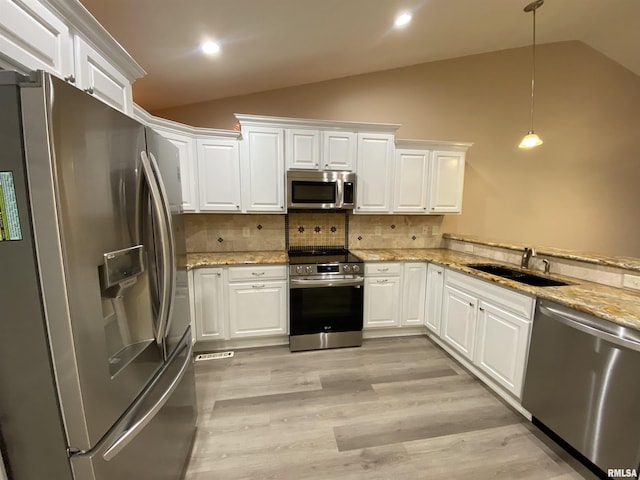 kitchen featuring appliances with stainless steel finishes, sink, lofted ceiling, pendant lighting, and white cabinets