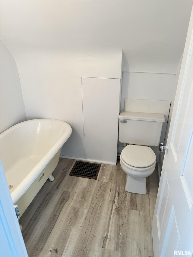 bathroom with a tub, toilet, and wood-type flooring