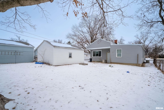 snow covered property featuring a chimney and an outbuilding