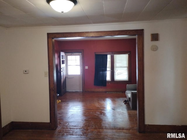 corridor featuring baseboards and dark wood-style flooring