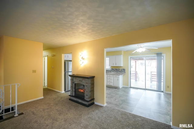 unfurnished living room featuring carpet, baseboards, a stone fireplace, and a textured ceiling