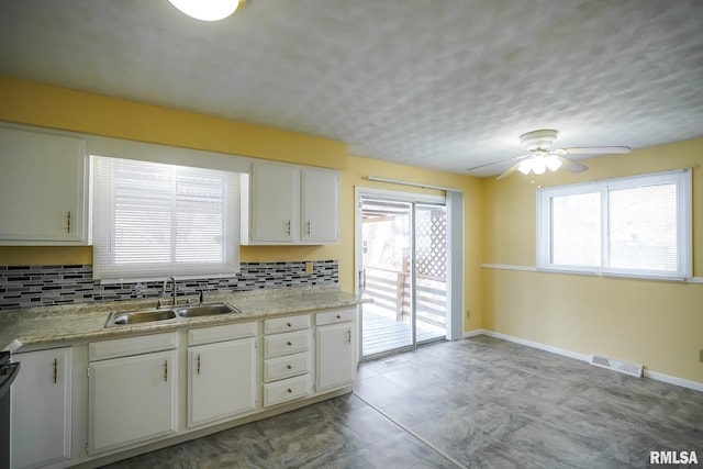 kitchen featuring tasteful backsplash, a sink, visible vents, and white cabinetry