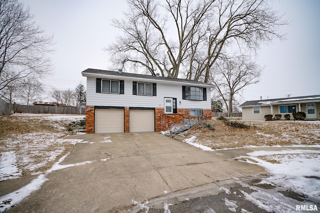 bi-level home featuring an attached garage, concrete driveway, and brick siding