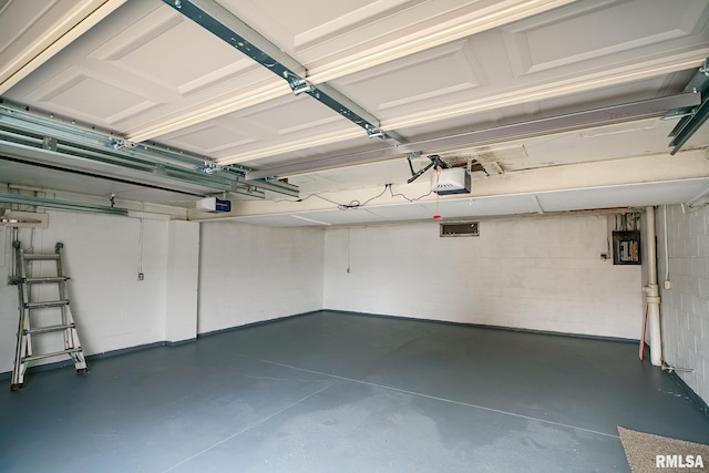 garage with concrete block wall, electric panel, and a garage door opener