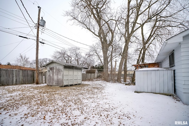 yard covered in snow featuring a shed, an outdoor structure, and a fenced backyard