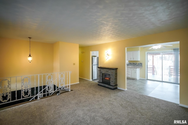 unfurnished living room featuring carpet floors, a glass covered fireplace, ceiling fan, and baseboards