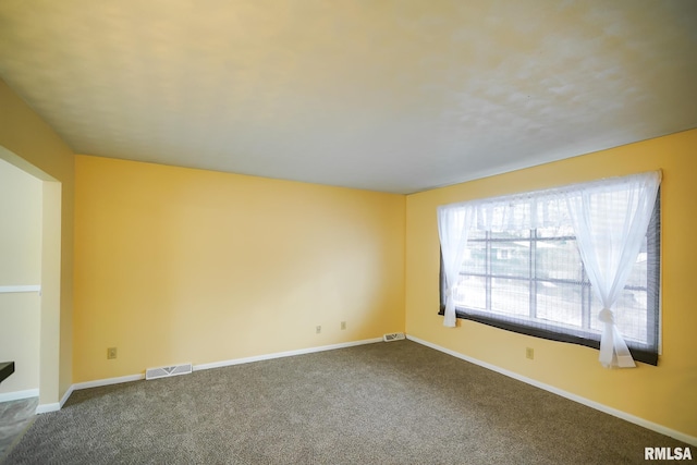 empty room with carpet, visible vents, and baseboards