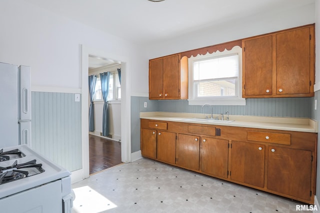 kitchen featuring white appliances, a sink, light countertops, brown cabinets, and light floors