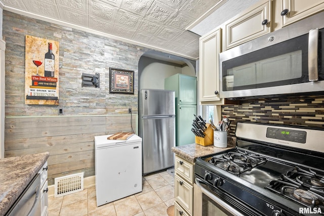 kitchen with visible vents, an ornate ceiling, cream cabinets, stainless steel appliances, and light tile patterned flooring