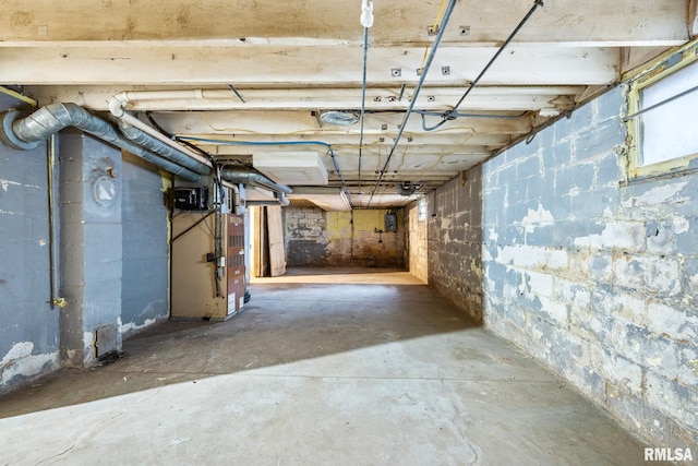 unfinished basement featuring concrete block wall and heating unit