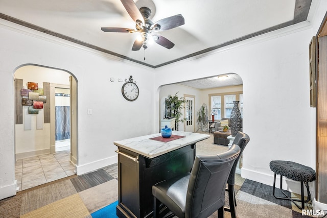 interior space with arched walkways, ceiling fan, ornamental molding, and baseboards