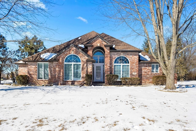 view of front of property with a shingled roof and brick siding