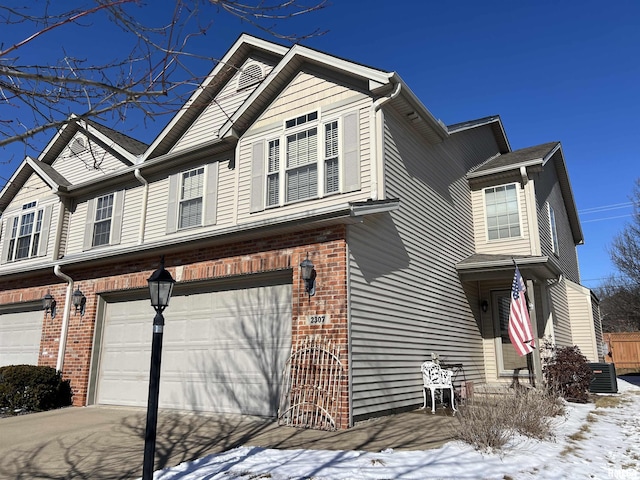 view of front facade with an attached garage, central AC unit, concrete driveway, and brick siding