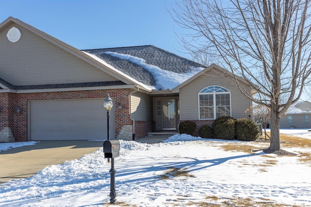 single story home with a garage, driveway, roof with shingles, and brick siding