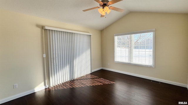 empty room with vaulted ceiling, dark wood-style flooring, visible vents, and baseboards