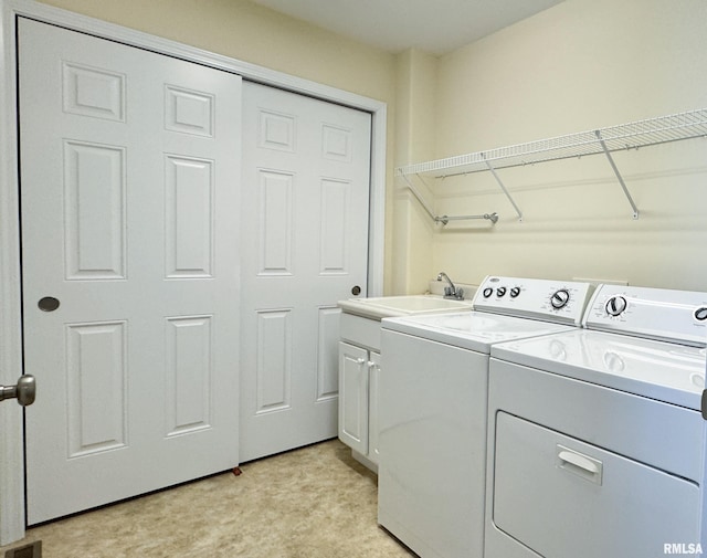 clothes washing area featuring a sink, light floors, washing machine and dryer, and cabinet space