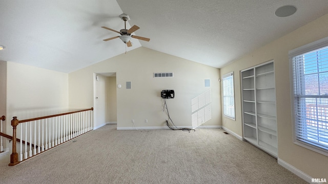 empty room with lofted ceiling, a wealth of natural light, and visible vents