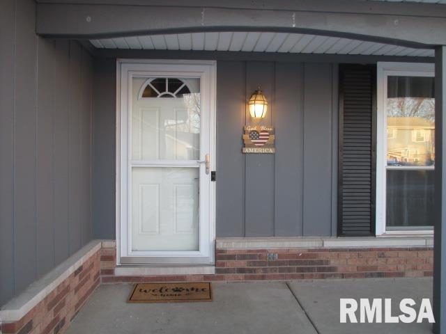 property entrance with board and batten siding and brick siding