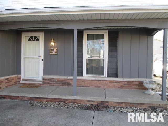 view of exterior entry featuring a porch and brick siding