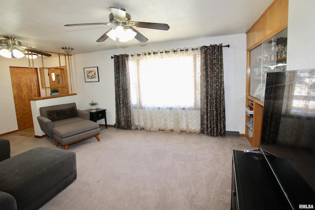 living area featuring baseboards, a ceiling fan, and light colored carpet