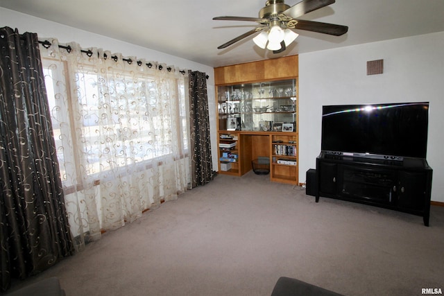 living room with carpet floors, visible vents, and a ceiling fan