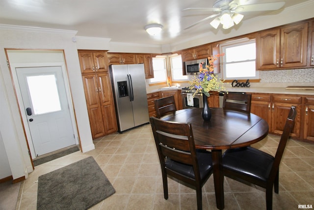 kitchen featuring brown cabinetry, appliances with stainless steel finishes, light countertops, and ornamental molding