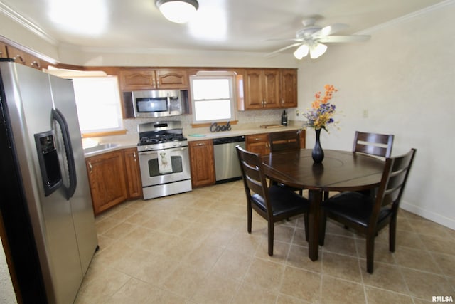 kitchen with stainless steel appliances, light countertops, ornamental molding, brown cabinets, and decorative backsplash