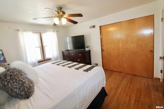 bedroom featuring a closet, wood finished floors, visible vents, and a ceiling fan