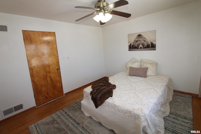 bedroom featuring a ceiling fan, visible vents, baseboards, and wood finished floors