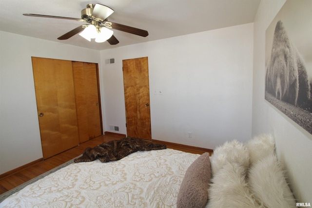 bedroom with baseboards, a closet, visible vents, and wood finished floors