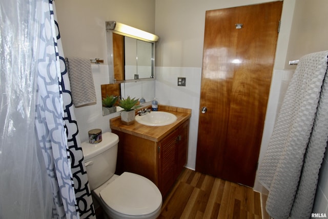 bathroom featuring toilet, vanity, tile walls, and wood finished floors