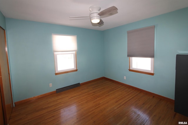 empty room featuring ceiling fan, baseboards, and dark wood finished floors