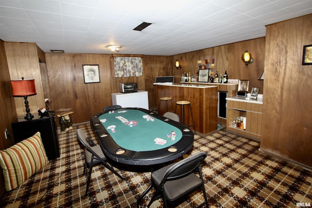 game room with dark floors, a dry bar, and wooden walls